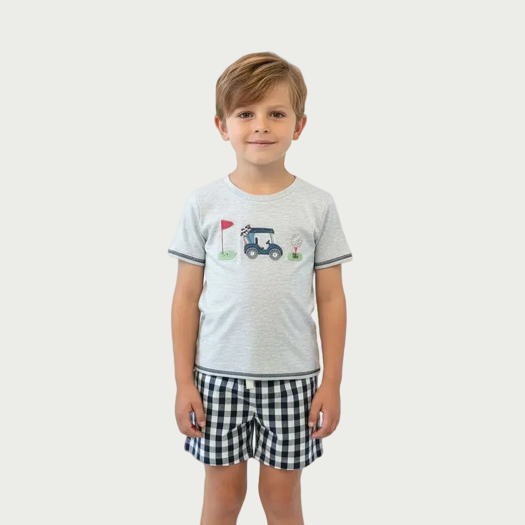 Child wearing a gray t-shirt with a tractor design and checkered shorts on a white background